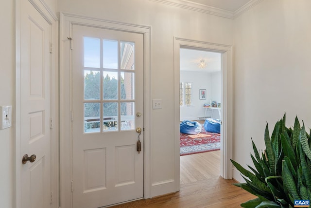 entryway featuring baseboards, light wood-style flooring, and crown molding