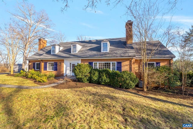 cape cod house with brick siding, central air condition unit, a chimney, and a front yard