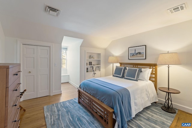 bedroom featuring light wood finished floors, visible vents, and baseboards