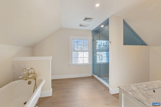 full bathroom featuring visible vents, wood finished floors, baseboards, lofted ceiling, and a freestanding bath