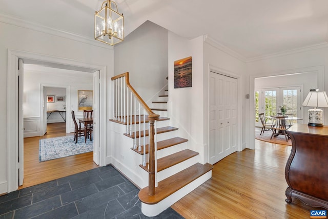 entrance foyer featuring stairway, crown molding, an inviting chandelier, and wood finished floors