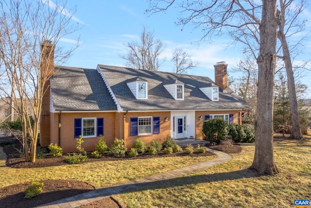 cape cod house featuring brick siding, a chimney, a front lawn, and a shingled roof