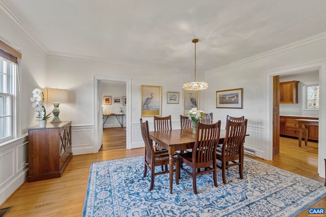 dining area featuring a healthy amount of sunlight, light wood-style flooring, and ornamental molding