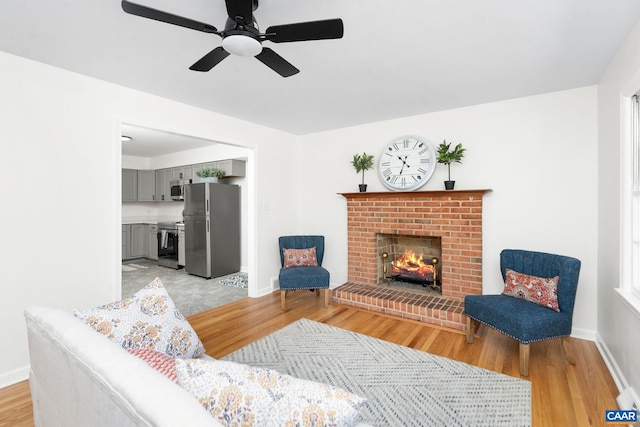 living room featuring light hardwood / wood-style floors, ceiling fan, and a fireplace