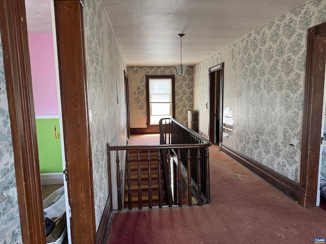 corridor with an upstairs landing, wallpapered walls, carpet floors, and baseboards