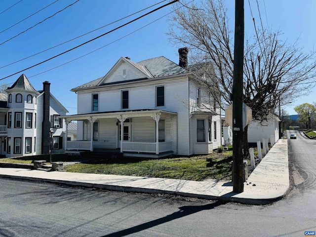 view of front facade featuring a chimney and a porch