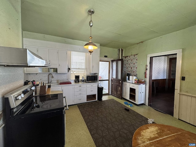 kitchen featuring hanging light fixtures, appliances with stainless steel finishes, light countertops, white cabinets, and a wainscoted wall