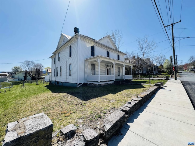 view of front of house featuring a porch, a front lawn, and a chimney