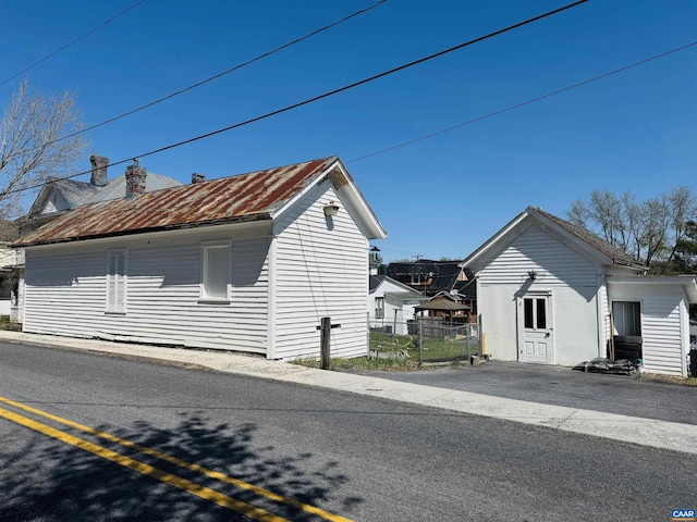 view of side of home featuring metal roof, a chimney, and fence