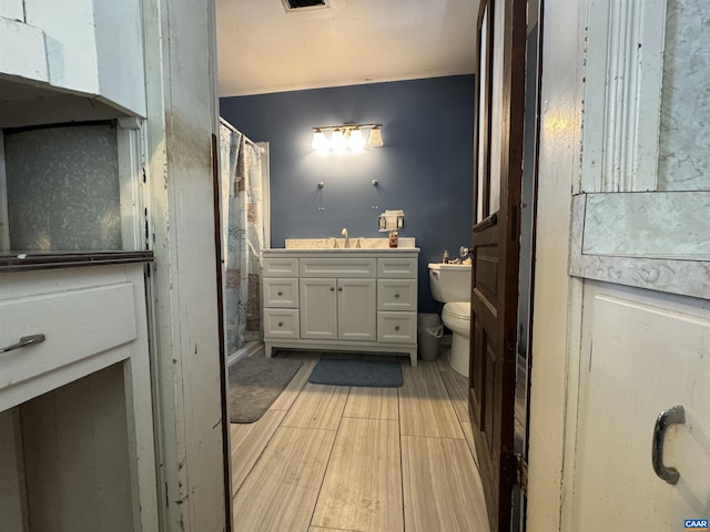 bathroom with vanity, toilet, visible vents, wood finished floors, and a shower with shower curtain