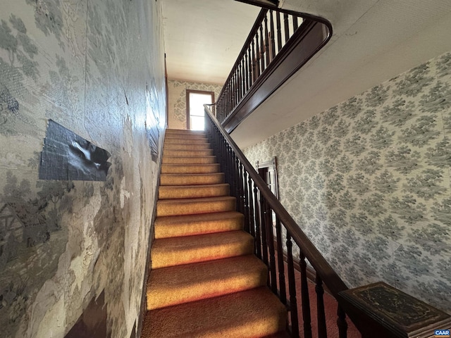 stairs featuring wallpapered walls