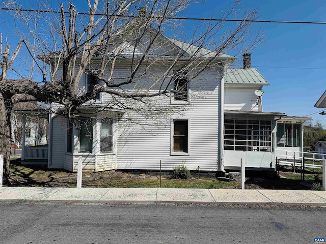 view of property exterior with a sunroom and a chimney