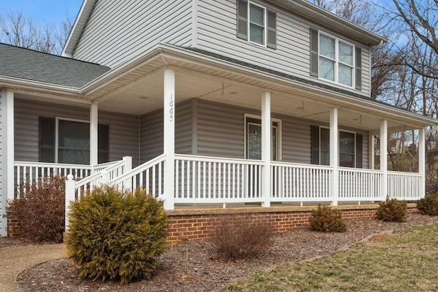 view of side of home with a shingled roof and a porch