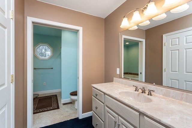 bathroom featuring vanity, toilet, and baseboards