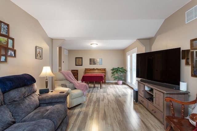 living area with lofted ceiling, light wood finished floors, visible vents, and baseboards