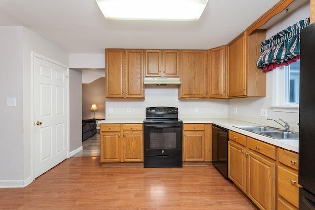 kitchen featuring light wood-type flooring, a sink, under cabinet range hood, and black appliances