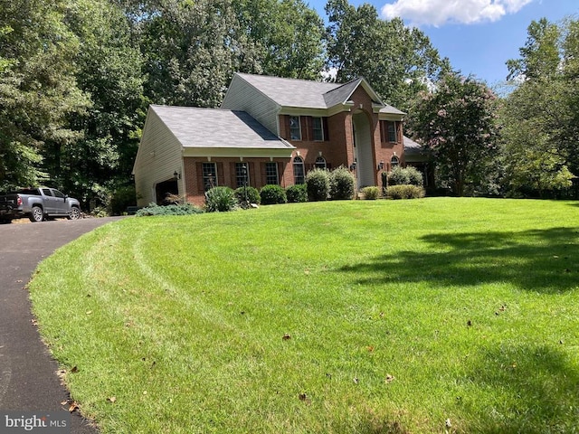 view of front of property with a garage, driveway, brick siding, and a front yard