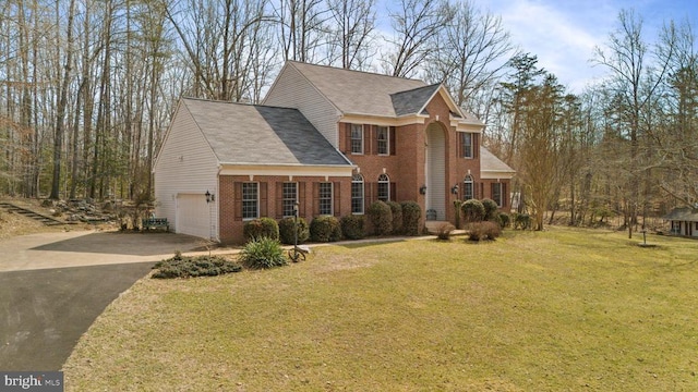 view of front facade with a garage, driveway, brick siding, and a front yard