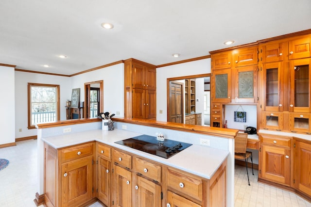 kitchen with ornamental molding, a kitchen island, built in desk, and black electric stovetop