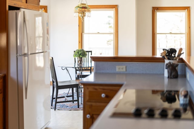 kitchen with white fridge, a chandelier, and black electric stovetop