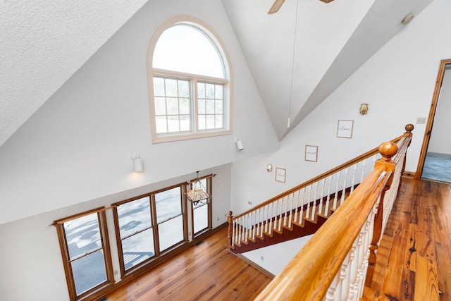 staircase with vaulted ceiling, ceiling fan, and wood-type flooring