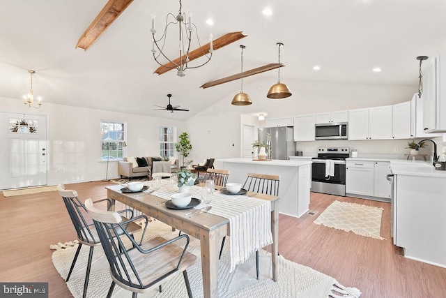 dining space featuring sink, light hardwood / wood-style flooring, beam ceiling, high vaulted ceiling, and ceiling fan with notable chandelier