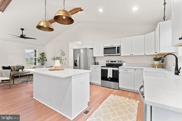 kitchen with sink, appliances with stainless steel finishes, pendant lighting, light hardwood / wood-style floors, and white cabinets