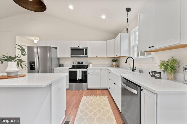 kitchen featuring sink, pendant lighting, stainless steel appliances, light stone countertops, and white cabinets