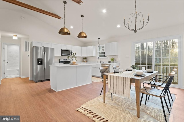 kitchen featuring sink, a center island, hanging light fixtures, stainless steel appliances, and white cabinets