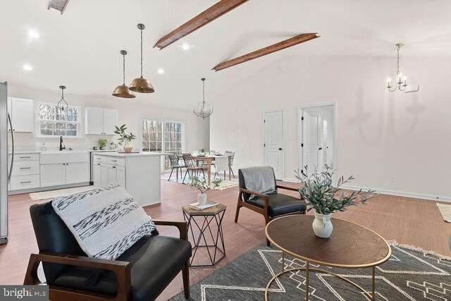 interior space featuring high vaulted ceiling, light wood-type flooring, sink, a chandelier, and beam ceiling