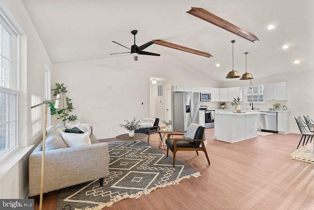 living room with ceiling fan, high vaulted ceiling, light hardwood / wood-style floors, and sink