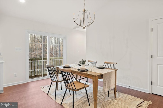 dining space with hardwood / wood-style floors and an inviting chandelier