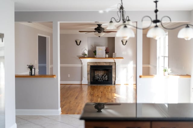 tiled living area featuring baseboards, a notable chandelier, a tile fireplace, and crown molding