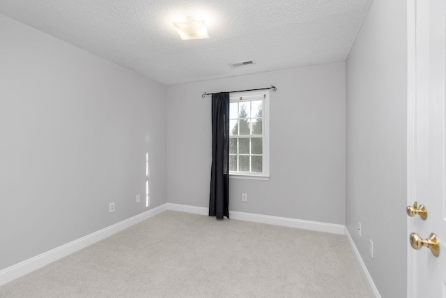 empty room with light colored carpet, visible vents, baseboards, and a textured ceiling