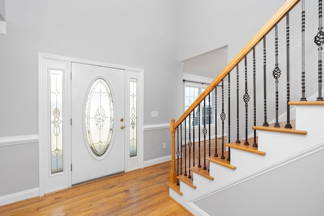 entryway with stairs, baseboards, a high ceiling, and wood finished floors