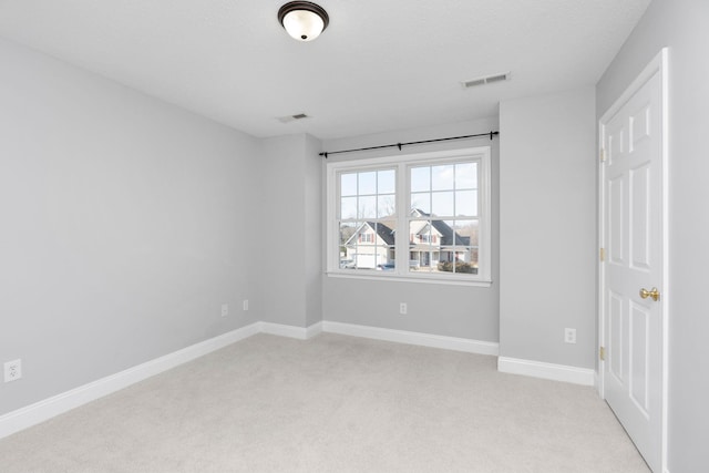 empty room featuring light carpet, visible vents, and baseboards