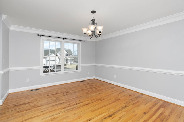 spare room featuring crown molding, baseboards, light wood-style flooring, and a notable chandelier