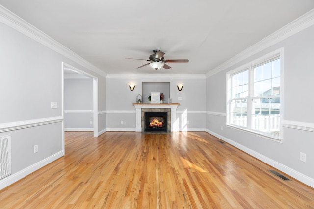 unfurnished living room with crown molding, a fireplace with flush hearth, visible vents, and light wood-style floors