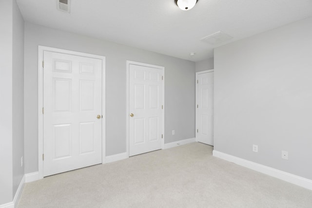 unfurnished bedroom with carpet floors, baseboards, and visible vents