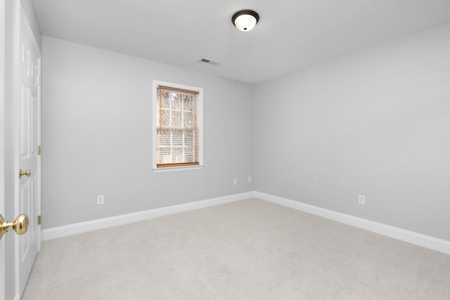 unfurnished room with baseboards, a textured ceiling, visible vents, and light colored carpet