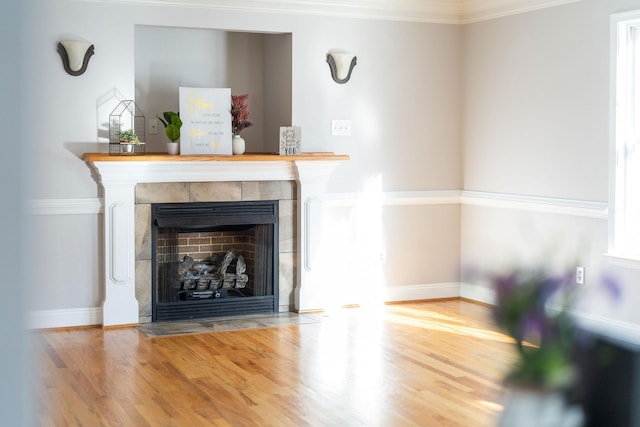 unfurnished living room featuring ornamental molding, a fireplace, wood finished floors, and baseboards