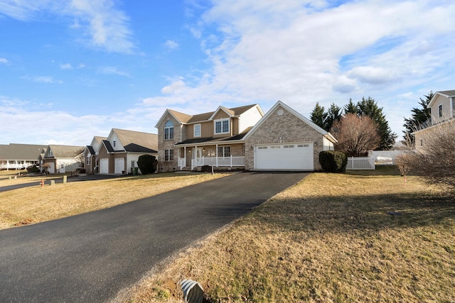 view of front of home featuring driveway, a residential view, fence, a front lawn, and brick siding