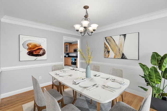 dining room featuring crown molding, light wood-style flooring, baseboards, and an inviting chandelier