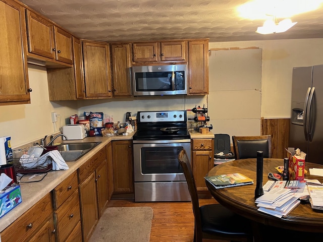 kitchen with sink, wood-type flooring, and appliances with stainless steel finishes