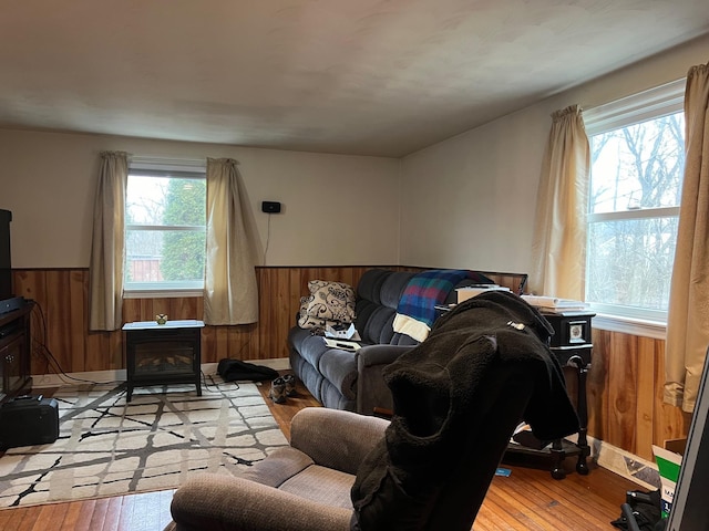 living room featuring a wood stove, light hardwood / wood-style floors, and wood walls