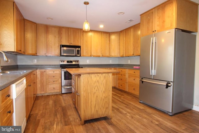 kitchen with stainless steel appliances, a center island, sink, and wood-type flooring