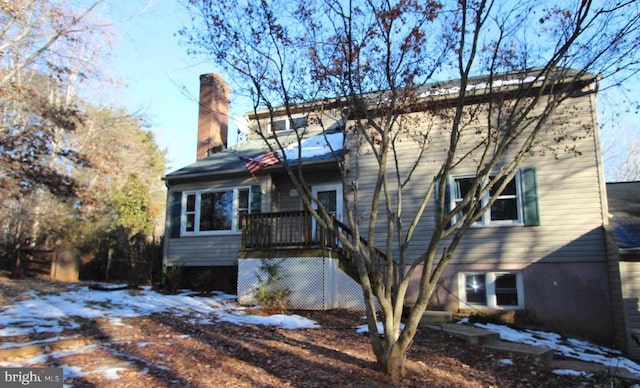 snow covered rear of property with a deck