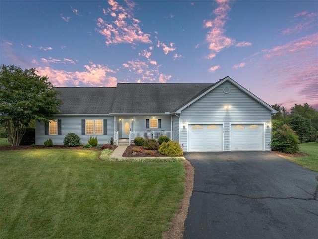 single story home featuring a porch, a garage, and a yard