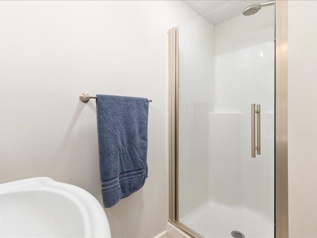 bathroom featuring a shower with door and sink