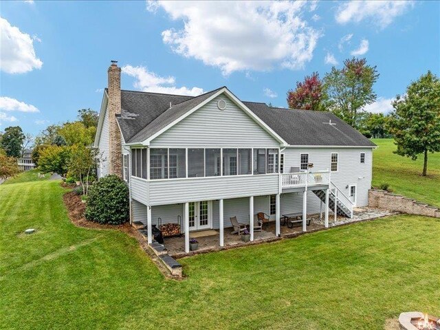 rear view of property with a sunroom, a lawn, a deck, and a patio area